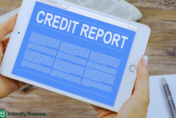 A woman's hand holding a tablet that shows "credit report" on the screen